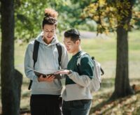 A diverse group of university students gathered around a holographic interface, working together on a complex project.