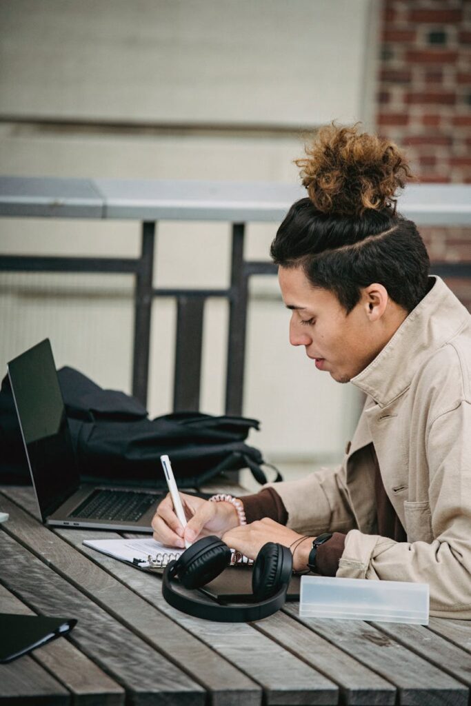 A close-up shot of a student's hands typing on a laptop, with complex code visible on the screen.
