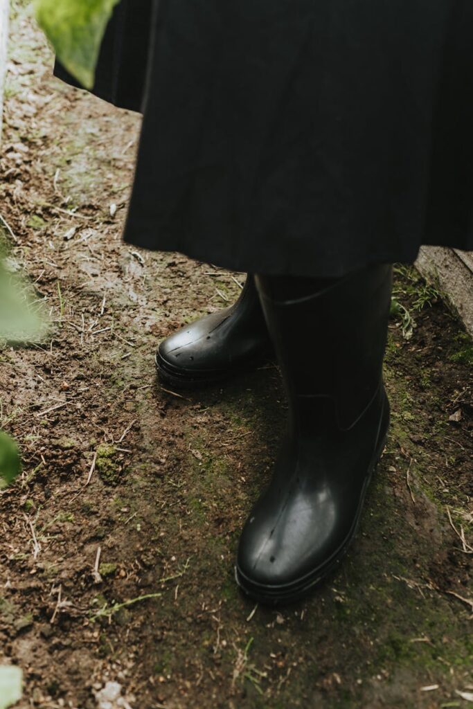 A detailed shot of brown leather boots crunching on a path covered in vibrant red and orange autumn leaves.