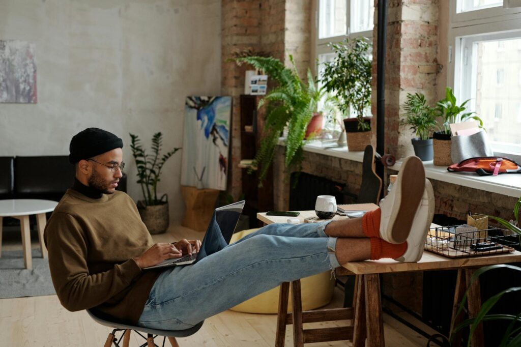 A woman smiling while working on her laptop at a cozy cafe, earning money online.