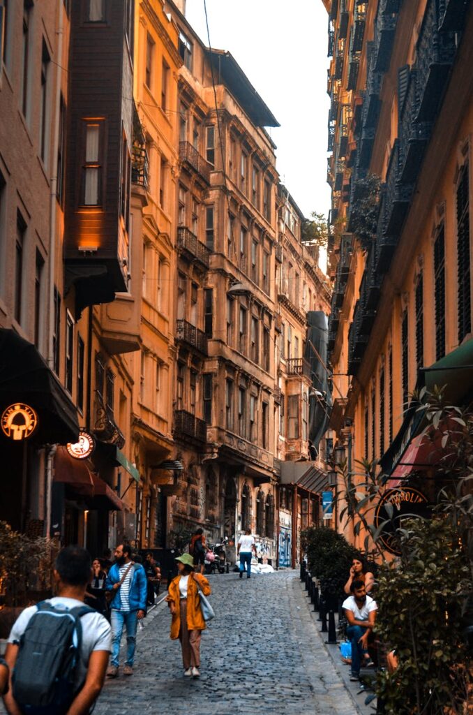 An empty, narrow cobblestone alleyway in a historic city with warm light from the rising sun.