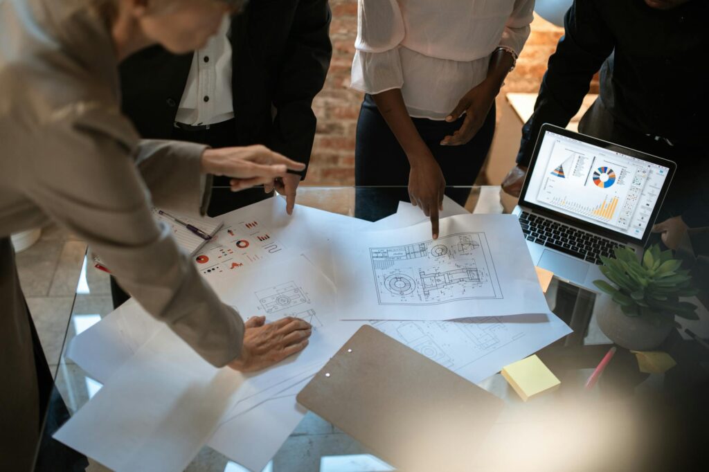 A focused small business owner sitting at a desk and pointing at a bar graph on their laptop screen.