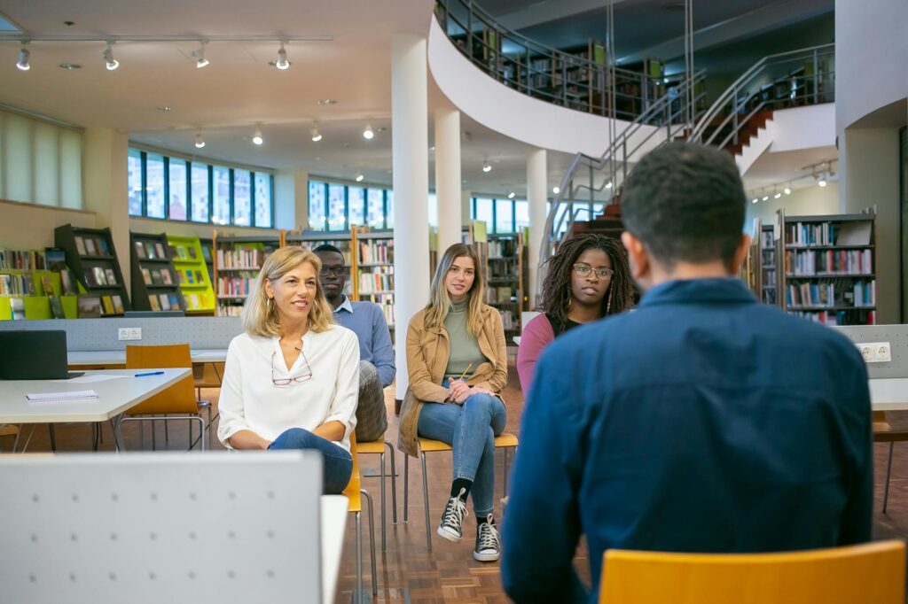 A team of four university students of different ethnicities pointing at a laptop screen during a collaborative session.