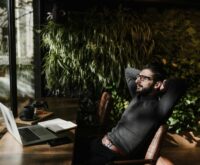 A business owner smiling while working on a laptop on a sunny beach, representing founder freedom.