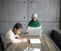 A young student focused on their laptop, working on an online data entry job from their dorm room.