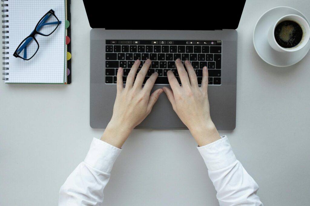 A detailed close-up shot of a student's hands quickly typing on a laptop keyboard, with blurred classroom lights in the background.