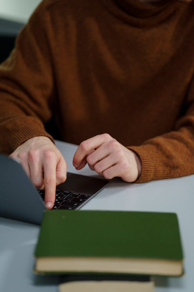 Overhead shot of a student's hands typing quickly on the illuminated keyboard of a modern laptop.