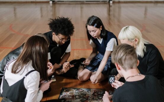 A diverse group of high school students gathered around a tablet, working together on a project.