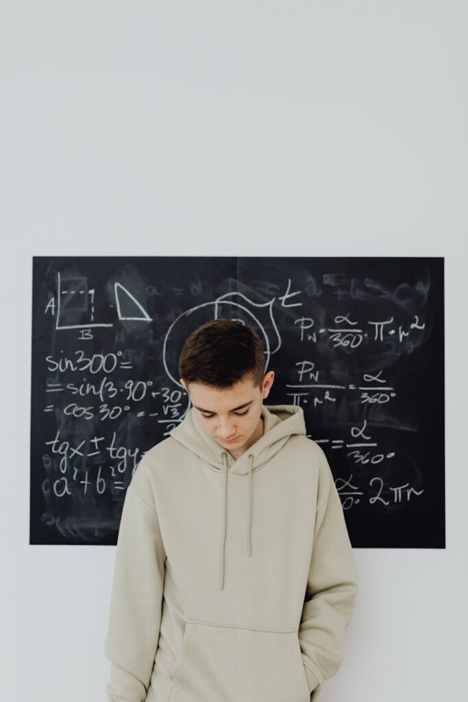 A young student with a furrowed brow staring at a large whiteboard covered in complex mathematical equations.