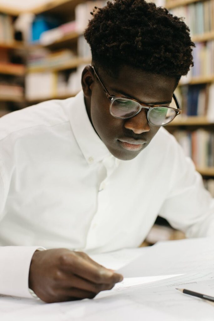 A student with their head in their hands, surrounded by stacks of textbooks and a glowing lamp, feeling overwhelmed.