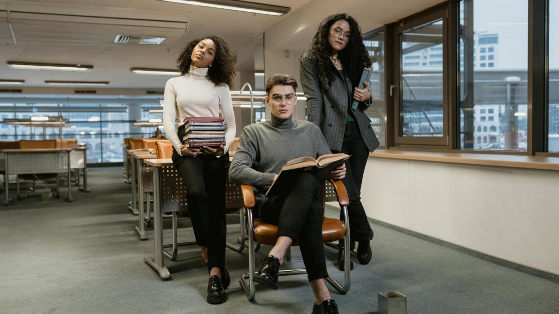 A diverse group of university students studying together at a large table in a sunlit library.
