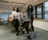 A diverse group of university students studying together at a large table in a sunlit library.
