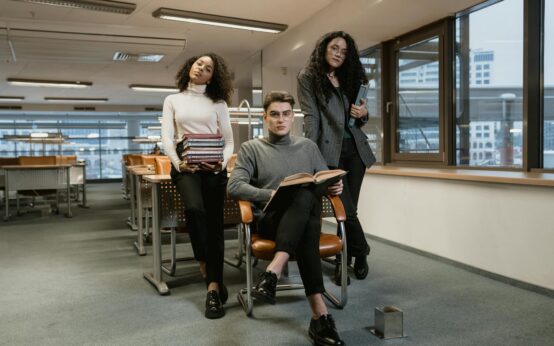 A diverse group of university students studying together at a large table in a sunlit library.