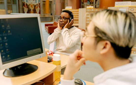 A diverse group of students working together around a table in a sunlit, modern library.