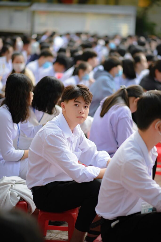 A young female student with headphones on, looking attentively towards the front of a lecture hall.