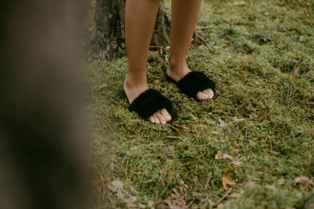 A first-person view of walking shoes on a park path, with early morning light filtering through the trees.