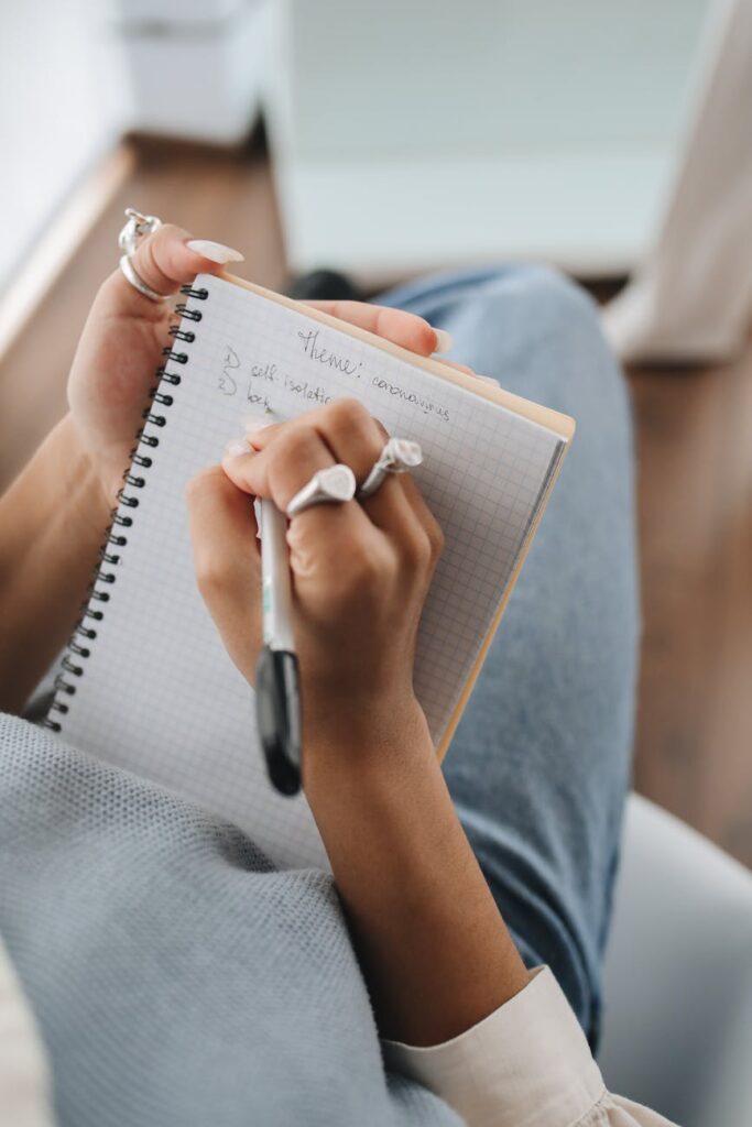 A detailed shot of a student's hands writing notes in a notebook during a university lecture.