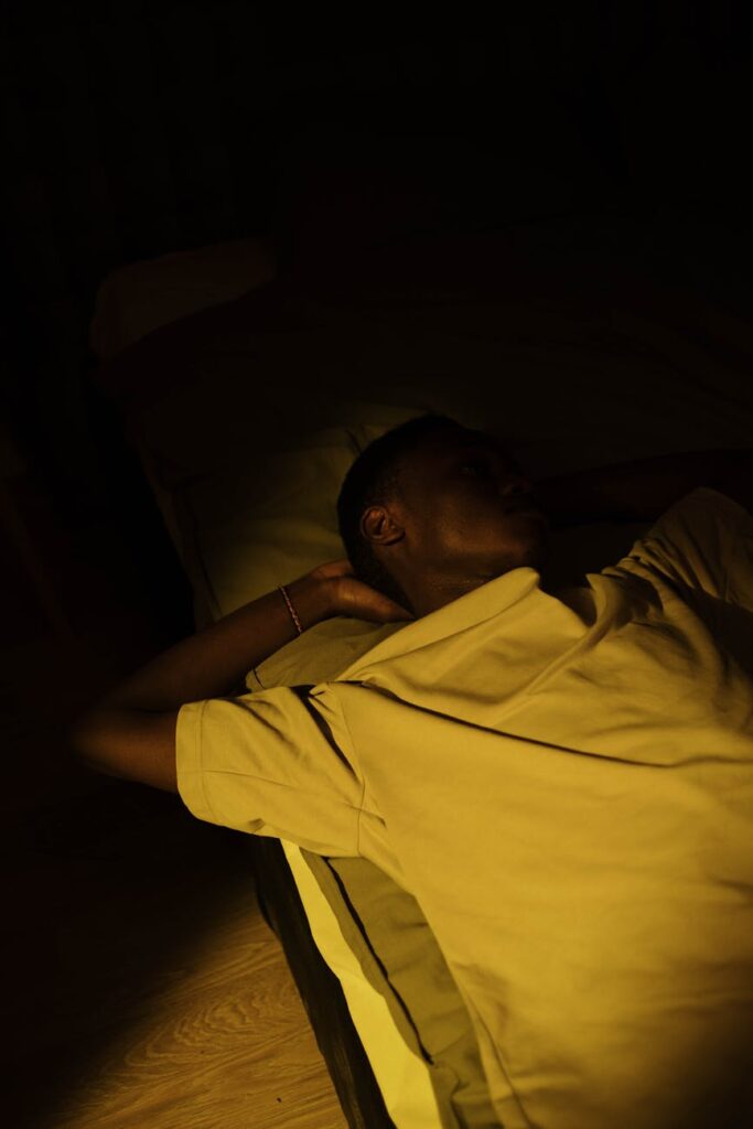 A young person sleeping soundly in a comfortable bed in a dimly lit, peaceful room.