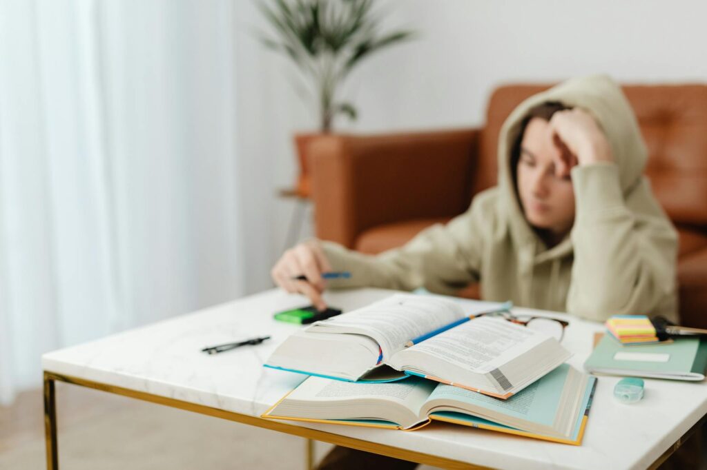 Close-up shot of a focused student's hand as they write detailed notes in a notebook in a quiet library setting.