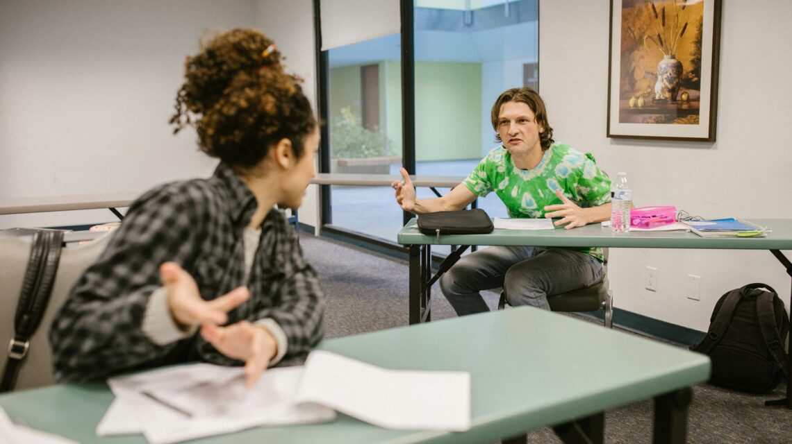 A diverse group of male and female university students working together around a table with their laptops.