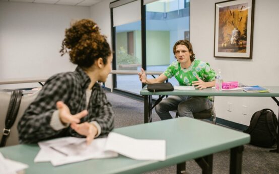A diverse group of male and female university students working together around a table with their laptops.
