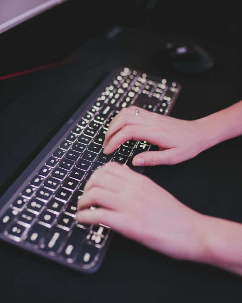 A detailed close-up shot of a person's hands typing quickly on a futuristic keyboard with blue backlighting.