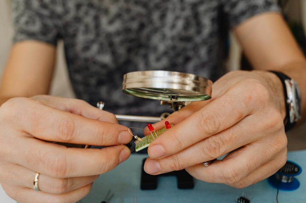 A detailed close-up shot of a student's hands carefully soldering a circuit board.