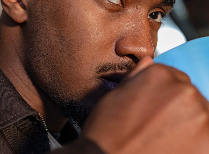 A person's feet propped up on a couch, holding a warm ceramic mug.