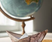 A traveler pointing at a destination on a large, vintage-style world map.