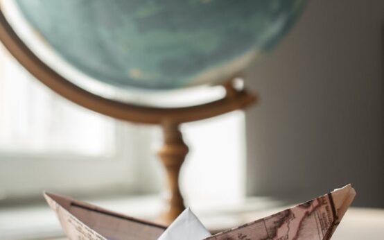 A traveler pointing at a destination on a large, vintage-style world map.