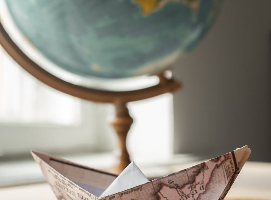 A traveler pointing at a destination on a large, vintage-style world map.