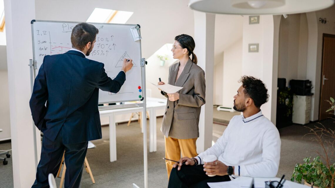 An independent filmmaker outlining a film's business plan on a large whiteboard in a creative office.