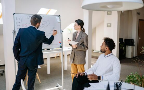 An independent filmmaker outlining a film's business plan on a large whiteboard in a creative office.