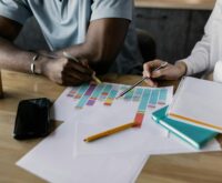 A diverse team of financial analysts pointing at a dynamic graph during a strategy meeting.