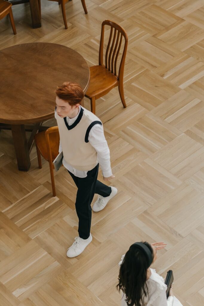 A multi-ethnic group of four university students collaboratively working on a project around a large wooden table in a sunlit library.