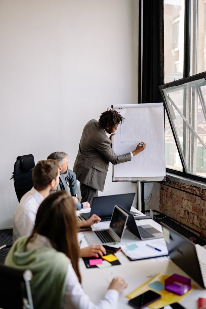 A diverse group of professionals actively engaged in a crisis planning session, using a whiteboard.