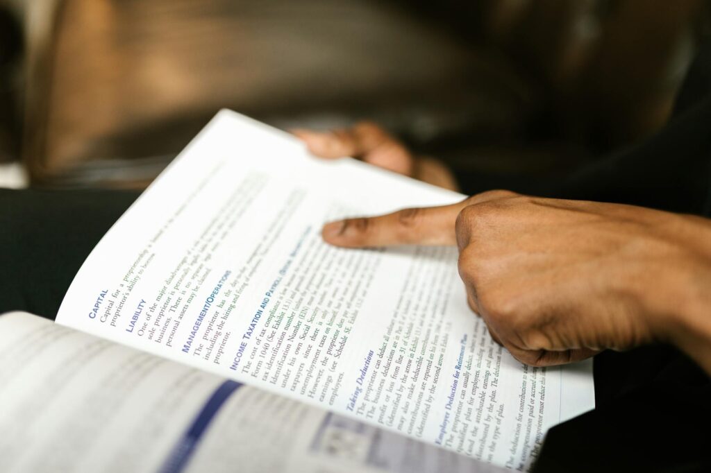 A close-up shot of a hand using a bright yellow highlighter on a page in a dense academic textbook.