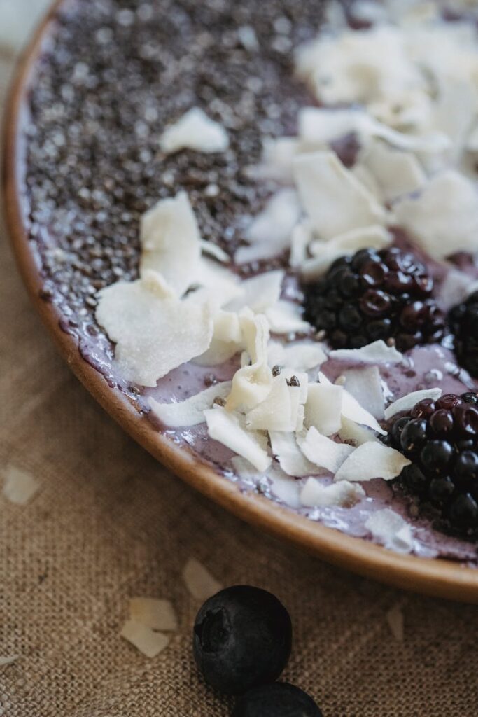 A warm bowl of oatmeal topped with fresh blueberries and strawberries placed beside a dumbbell on a yoga mat.