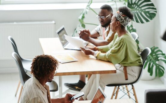 A male student speaks earnestly with a female professor in a sunlit university office.