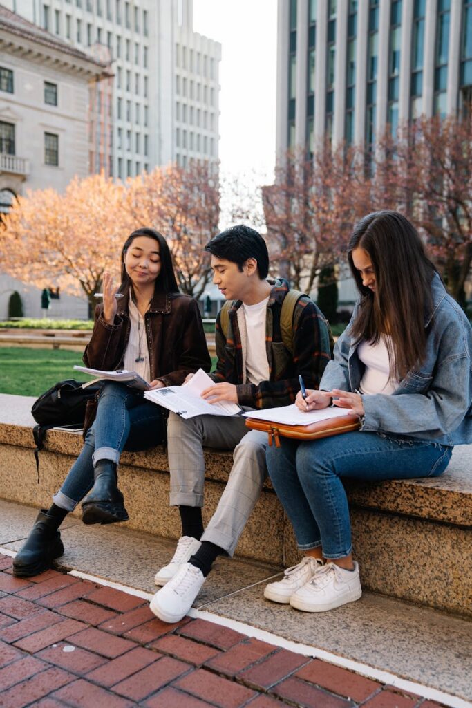 Four university students of different ethnicities laughing and working together on a project.