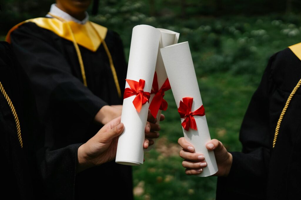 A joyful group of diverse friends in graduation gowns tossing their caps in the air.