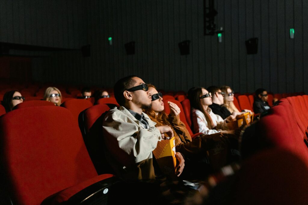 The silhouette of an engaged audience watching a film on a large screen at an independent film festival.