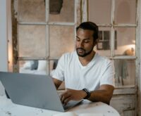 A person's hands typing on a laptop keyboard, representing online data entry work.