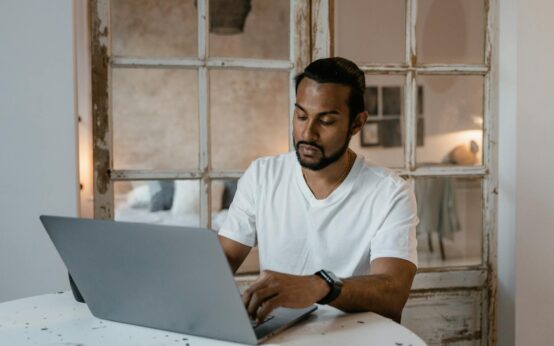 A person's hands typing on a laptop keyboard, representing online data entry work.