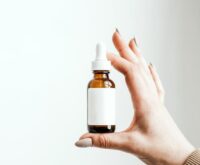 A person with glasses holding a can and closely reading the nutrition and ingredients label.