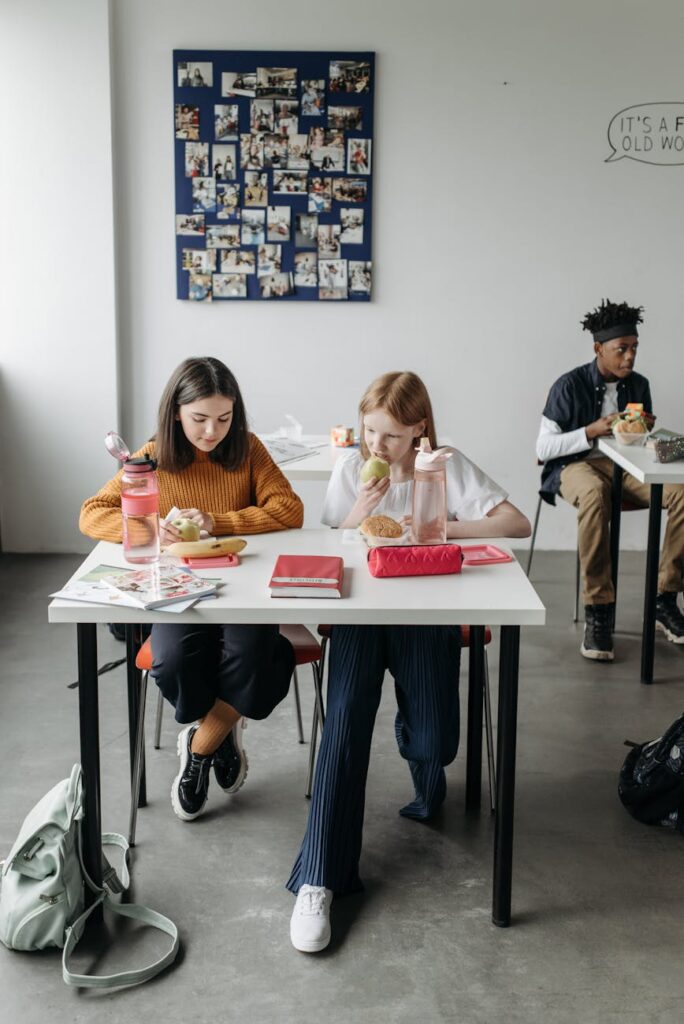 Several young students sit in a bright, modern classroom, each engaged with their personal laptop.