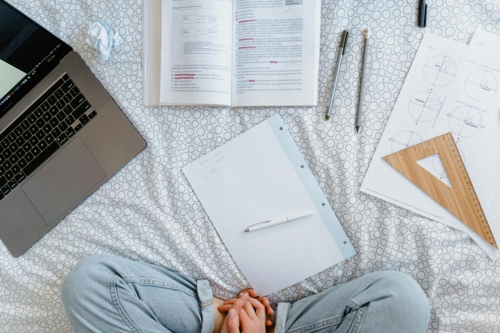 A recent graduate with a determined expression working on a freelance project on their laptop in a bright co-working office.