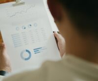 A person analyzing financial charts on a laptop, with icons of coins and dollar signs, illustrating online earnings.