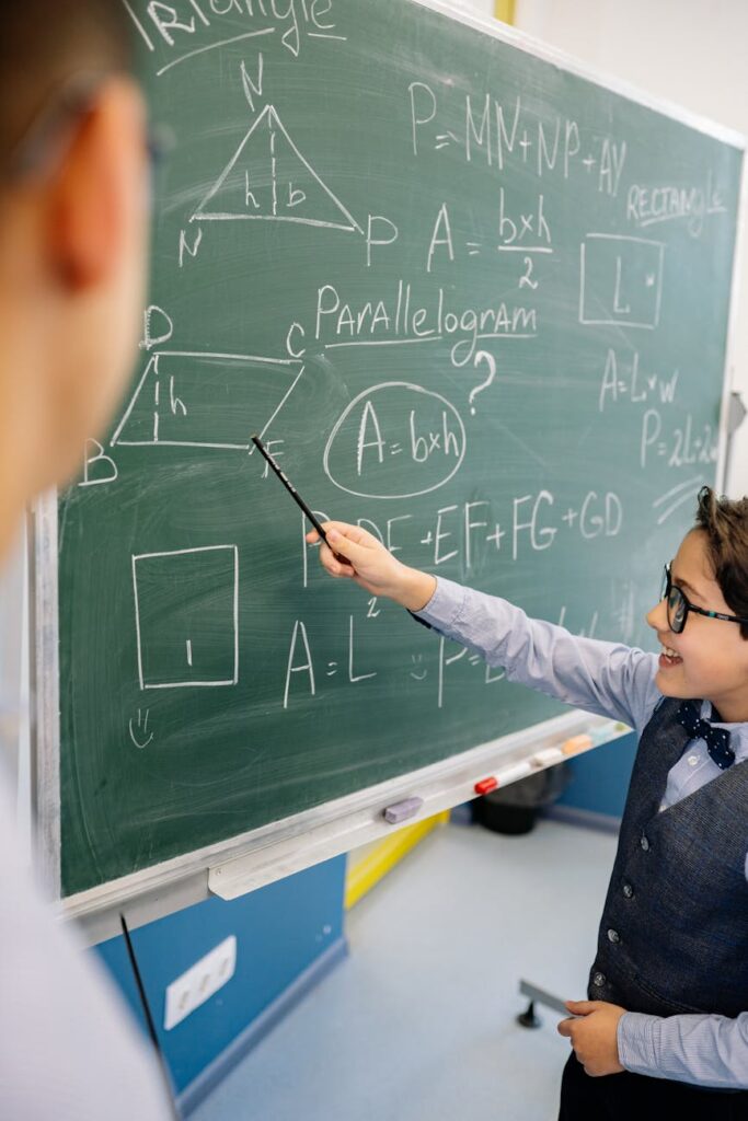 A confident student stands at the front of a modern classroom, pointing to a presentation on a large screen while addressing their peers.