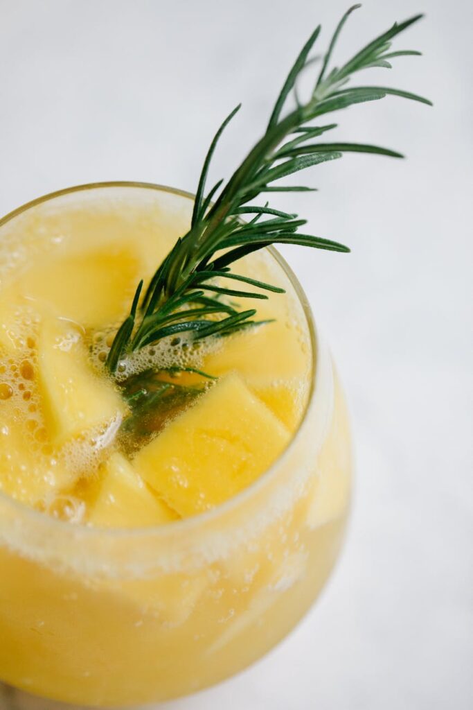 A tall glass of iced tea with a slice of lemon sits beside a vibrant quinoa salad in a white bowl.